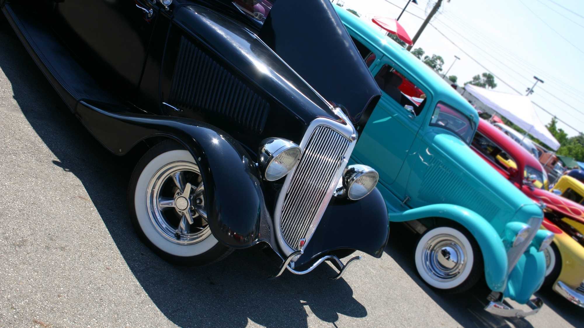 Autos clásicos negros y verde azulado y Hot Rods estacionados en una exhibición de autos