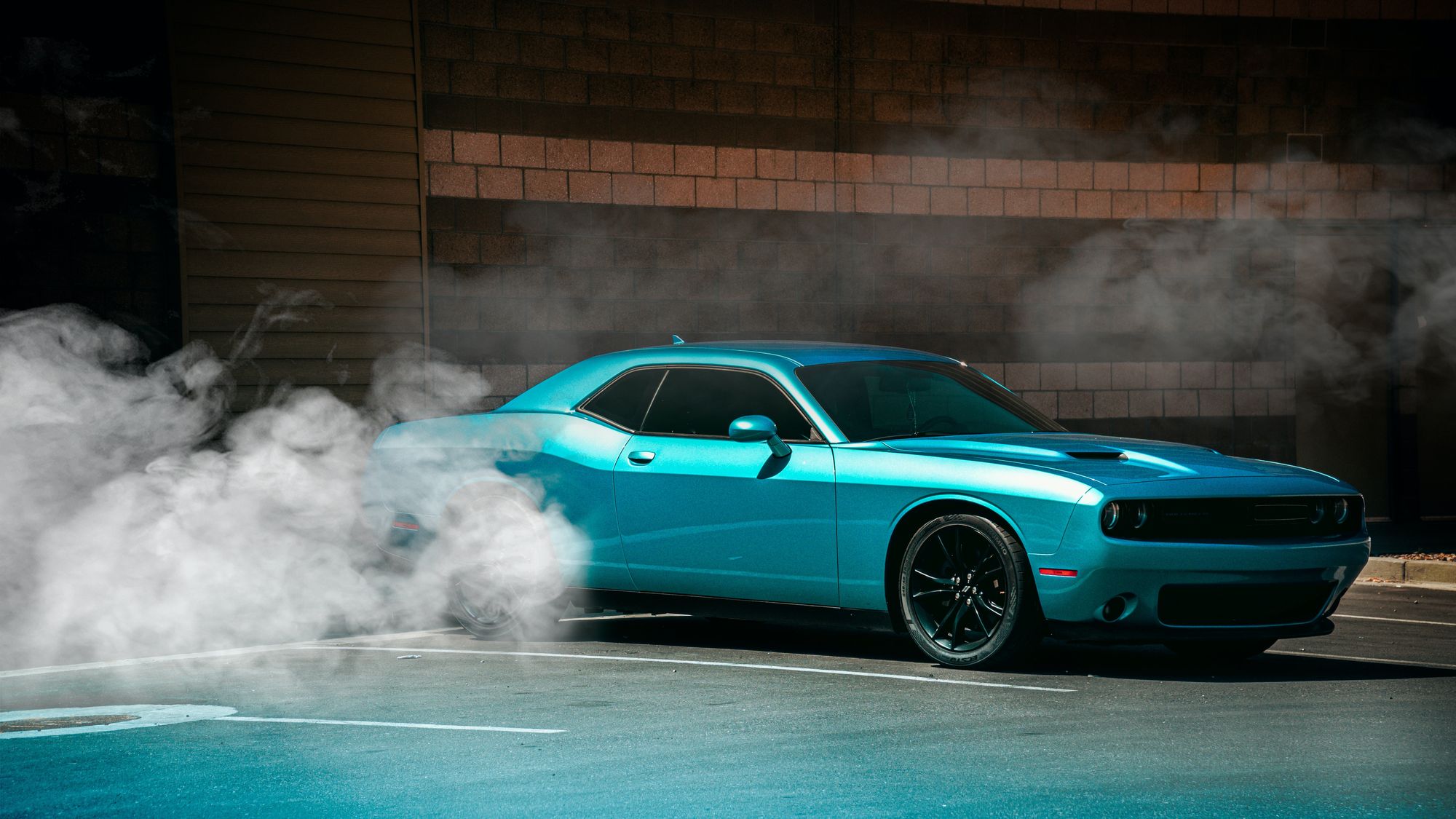 Dodge Challenger azul en un lugar de estacionamiento con humo alrededor.