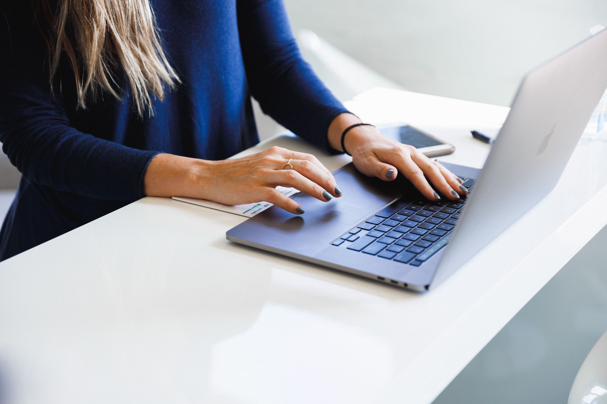 Mujer en el escritorio blanco usando una computadora portátil.