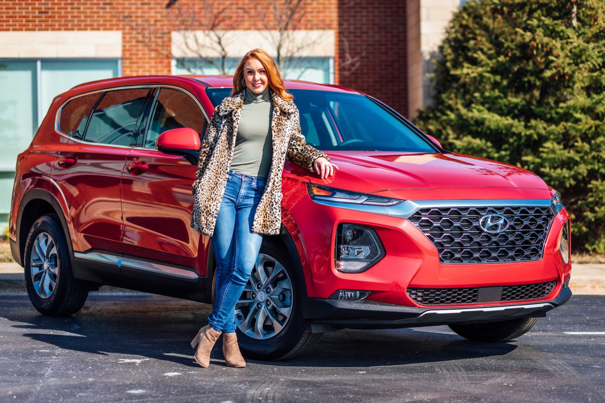 Mujer pelirroja junto a un Hyundai rojo.