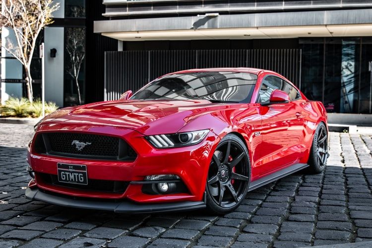 Ford Mustang GT personalizado rojo estacionado en adoquines
