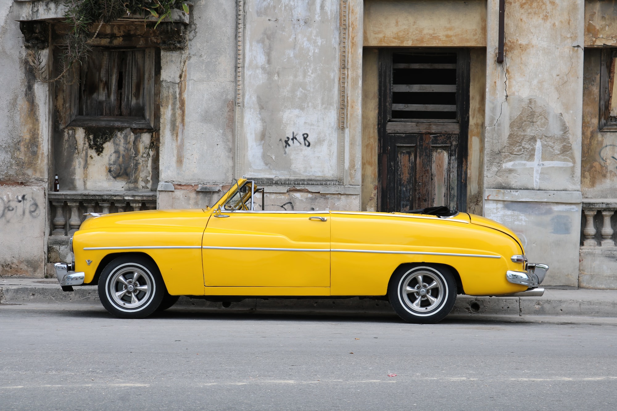 Coche convertible clásico amarillo frente al antiguo edificio de cemento